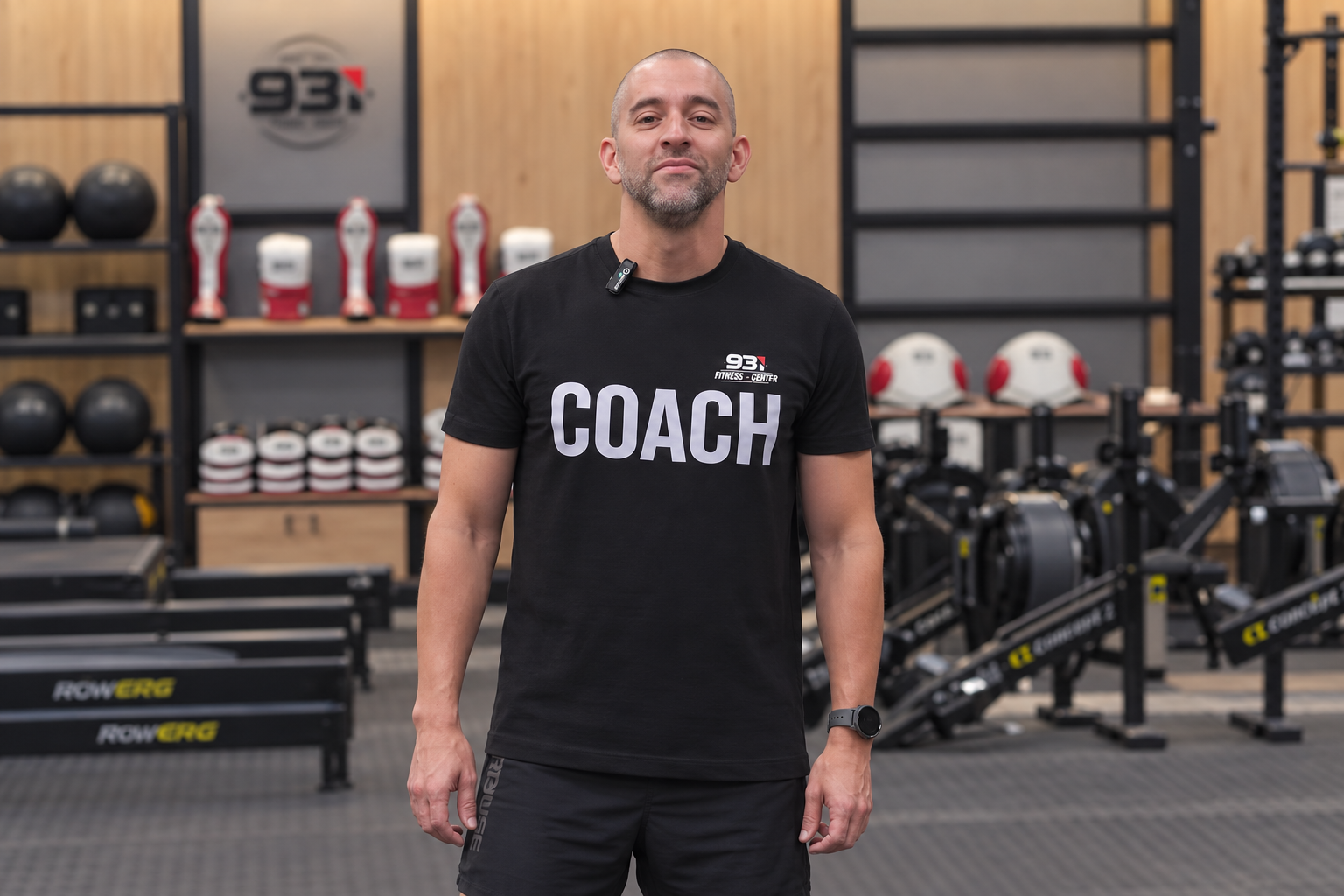 Entrenador de pie en un gimnasio con equipamiento deportivo